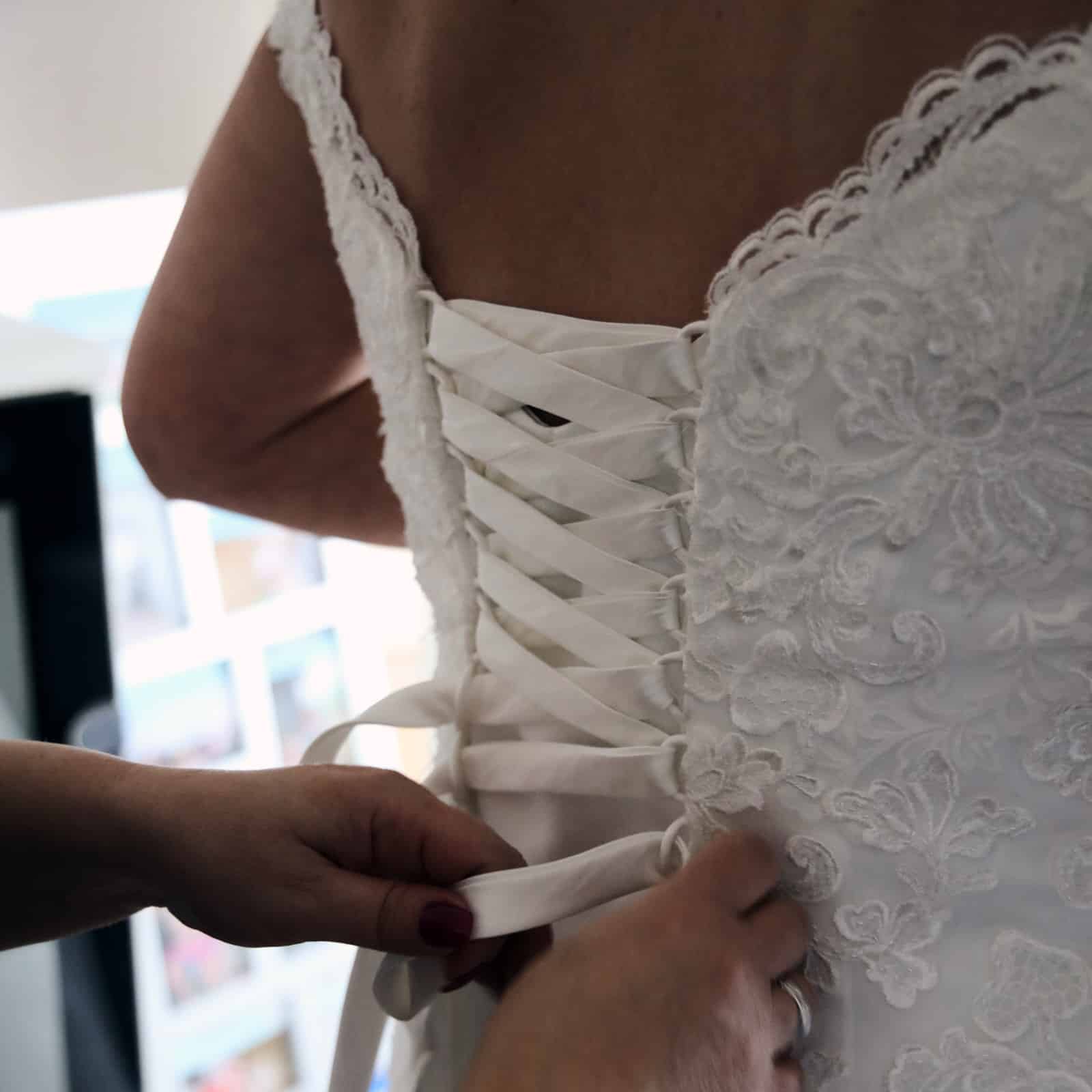 Hochzeitsreportage Brautkleid wird zugeschnürt